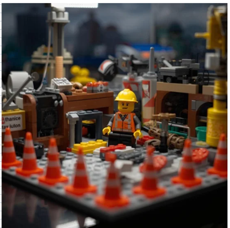 l'immagine di una costruzione LEGO fatta di mattoncini. Al centro c'è un lavoratore con giubotto catarifrangente e caschetto, intorno lo spazio è delimitato da coni, lo sfondo non è definito ma evoca una fabbrica. Questa immagine serve a pubblicizzare il corso lego serious play sui near miss, di cui parla l'articolo. 